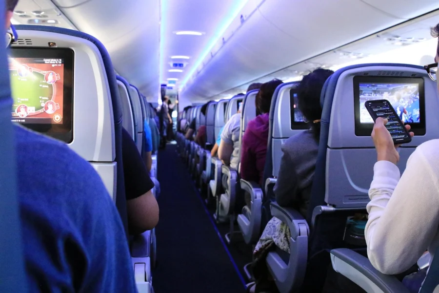 Anxious passenger looking at a smartphone while sitting in an airplane seat